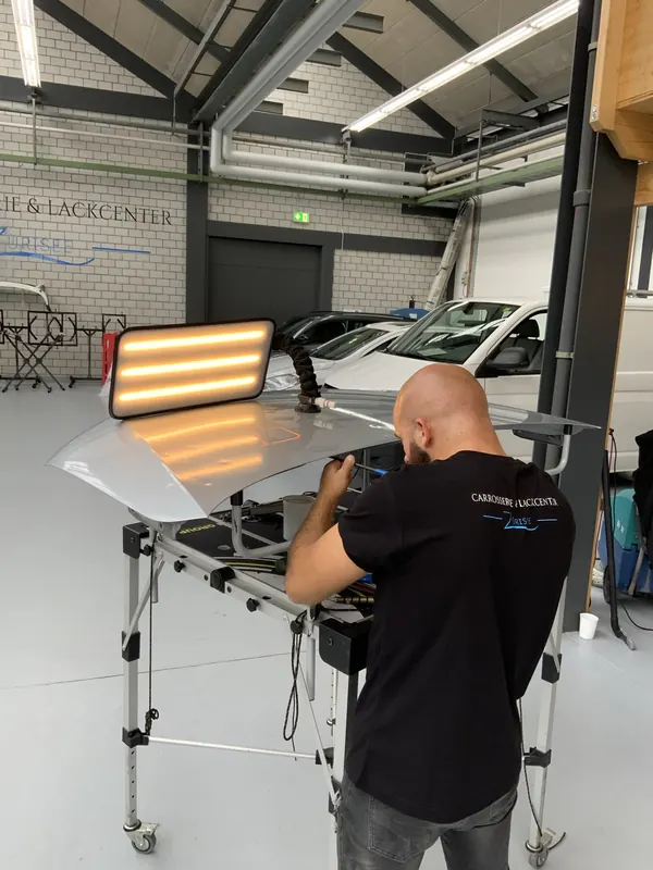 Dellentechniker drückt Hagelschaden an einem Kundenfahrzeug